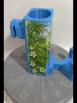 A rotating light blue Paddle Saver™ with an attached Dink & Slam skin. The skin has a tropical theme with palm trees, pickleball paddles and ball.