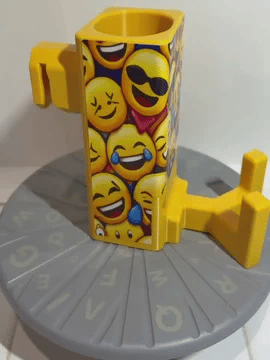 A rotating yellow Paddle Saver™ with an attached Pickleball Party skin. The skin has an emoji theme with many different emojis celebrating.